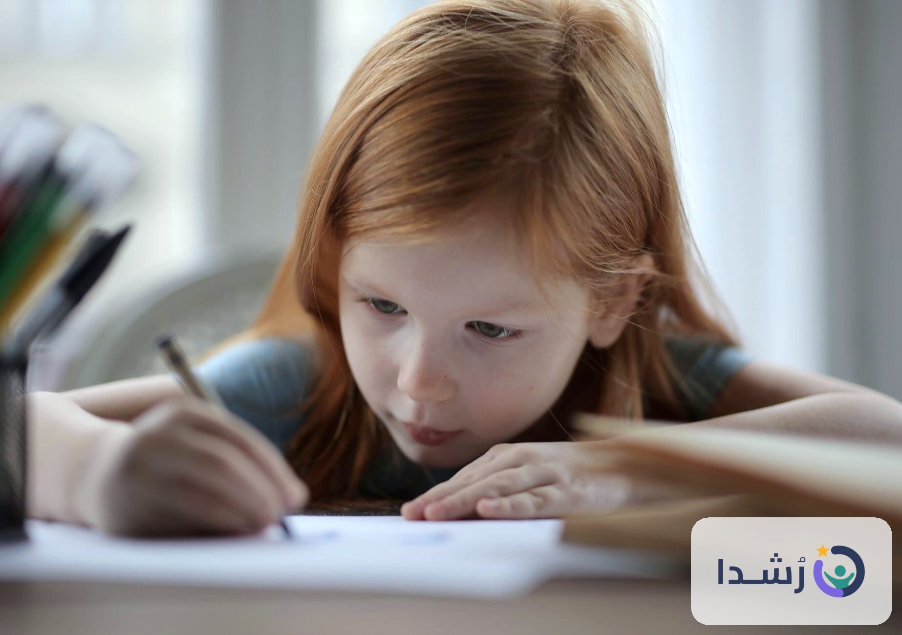 طفلة تكتب بتركيز على ورقة بيضاء