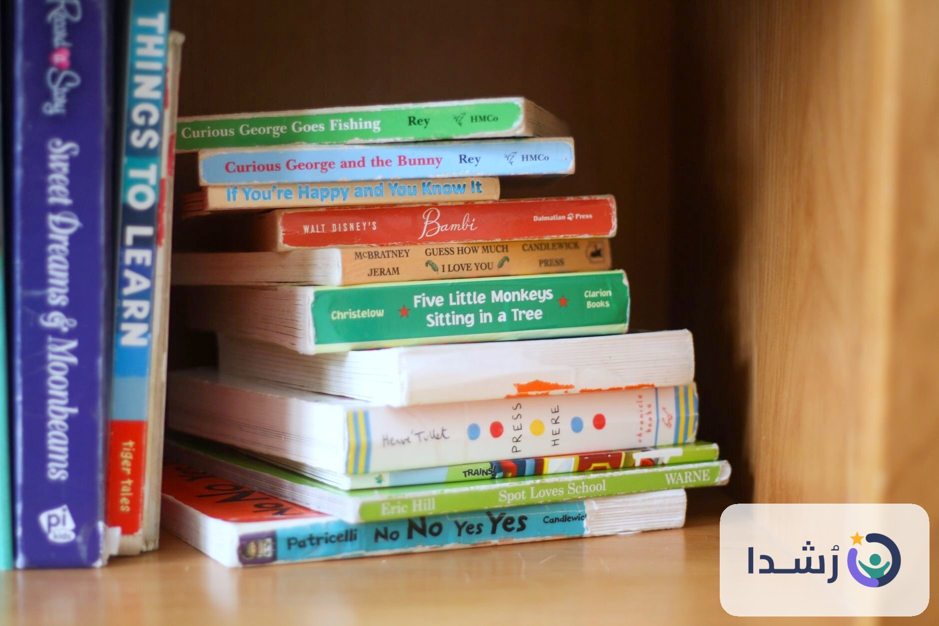 مجموعة من الكتب التعليمية للأطفال على رف خشبي