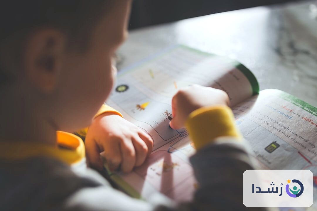 طفل يتعلم من كتاب تعليمي في بيئة منزلية.
