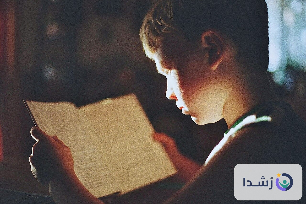 طفل يقرأ كتابًا في ضوء خافت