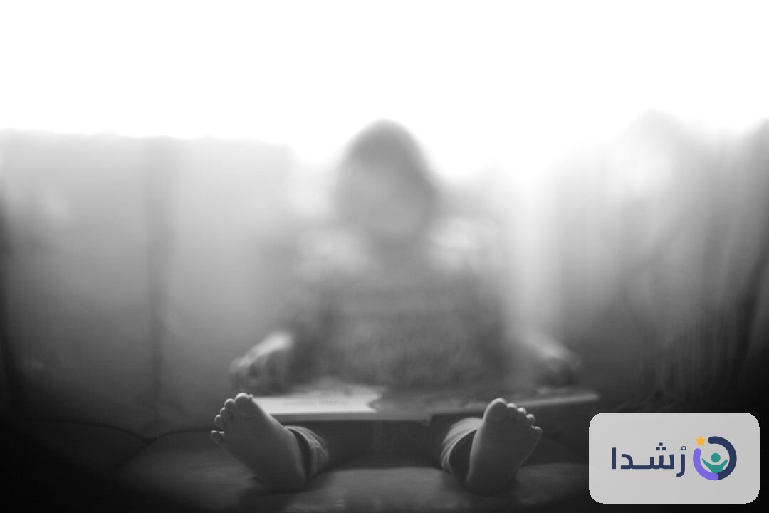 طفل يجلس على الأريكة ويقرأ كتابًا في غرفة مضيئة