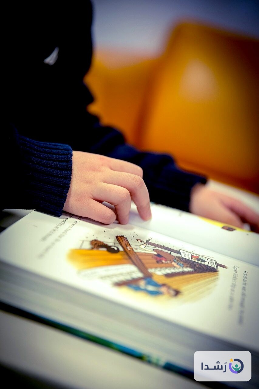 يد طفل تتصفح كتابًا ملونًا مع رسومات جذابة.